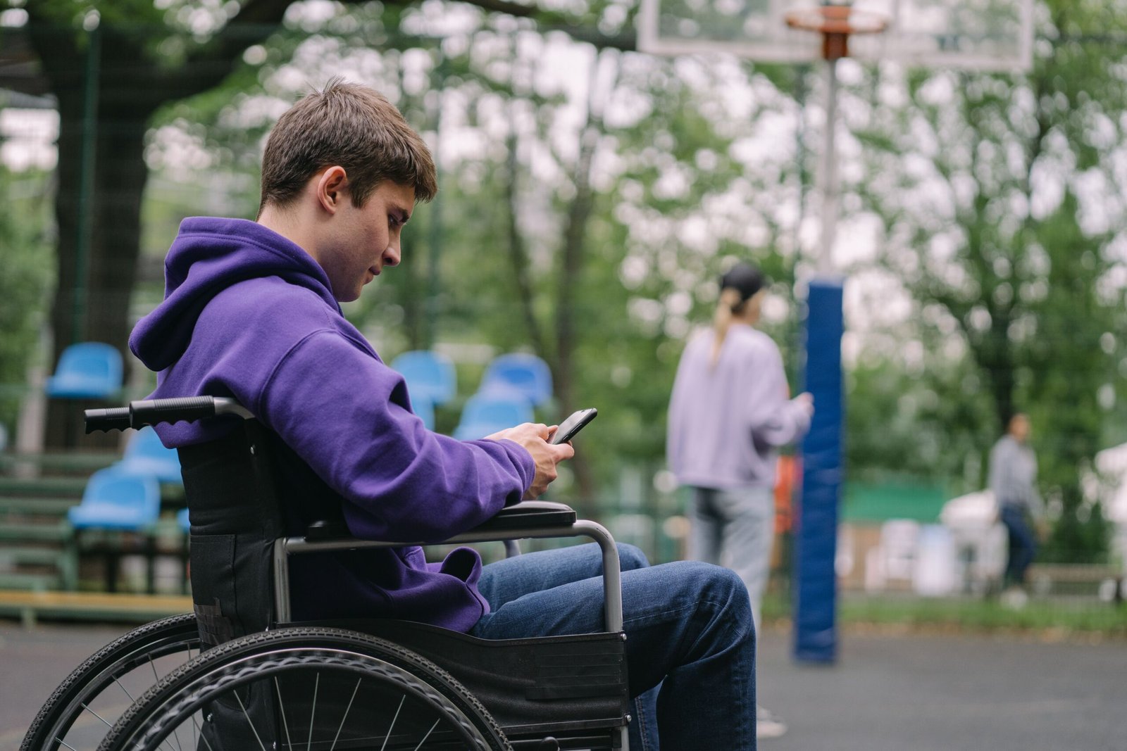 Un jeune homme en fauteuil roulant consulte son téléphone