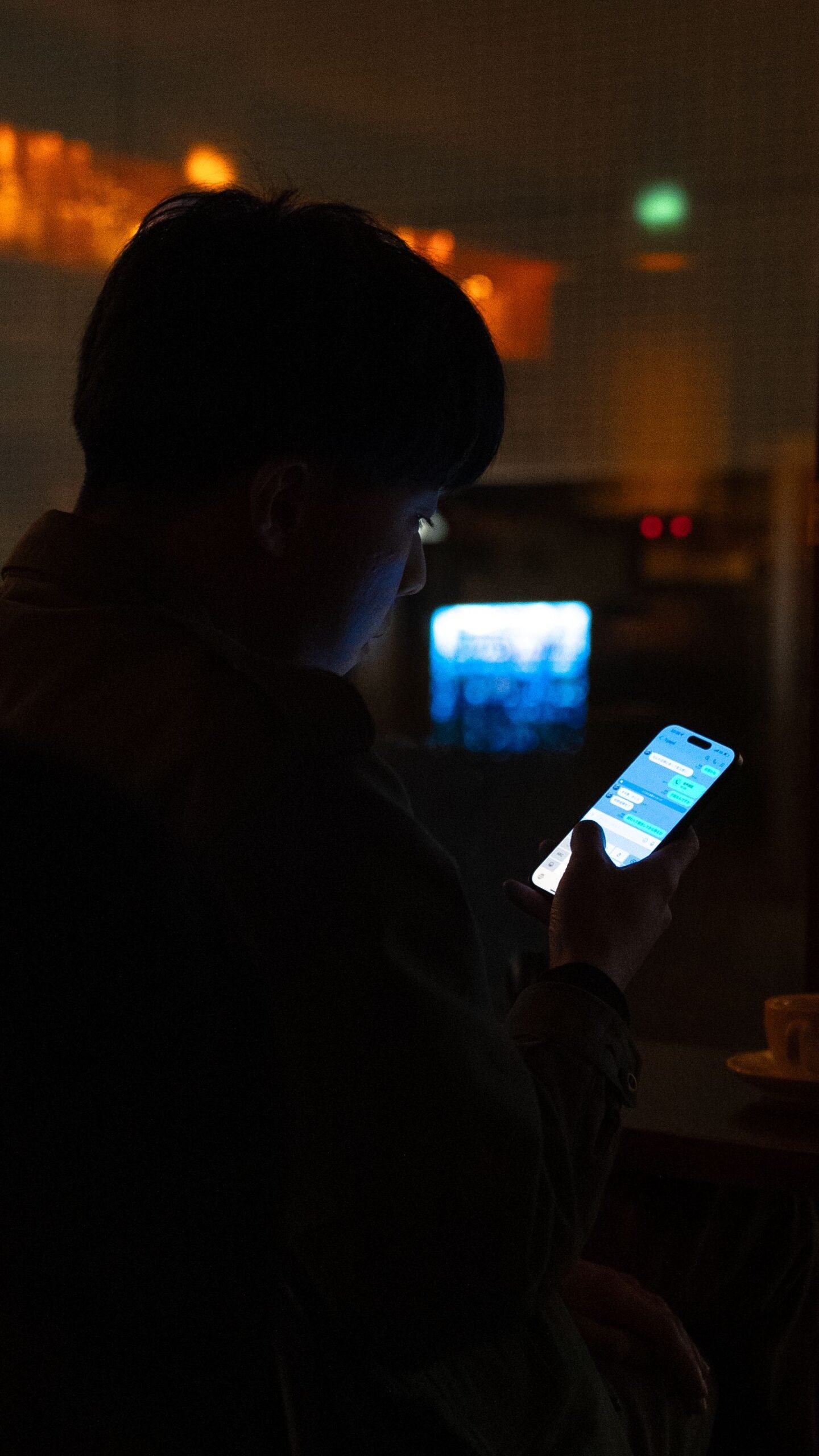 Une personne isolée regarde son téléphone dans le noir